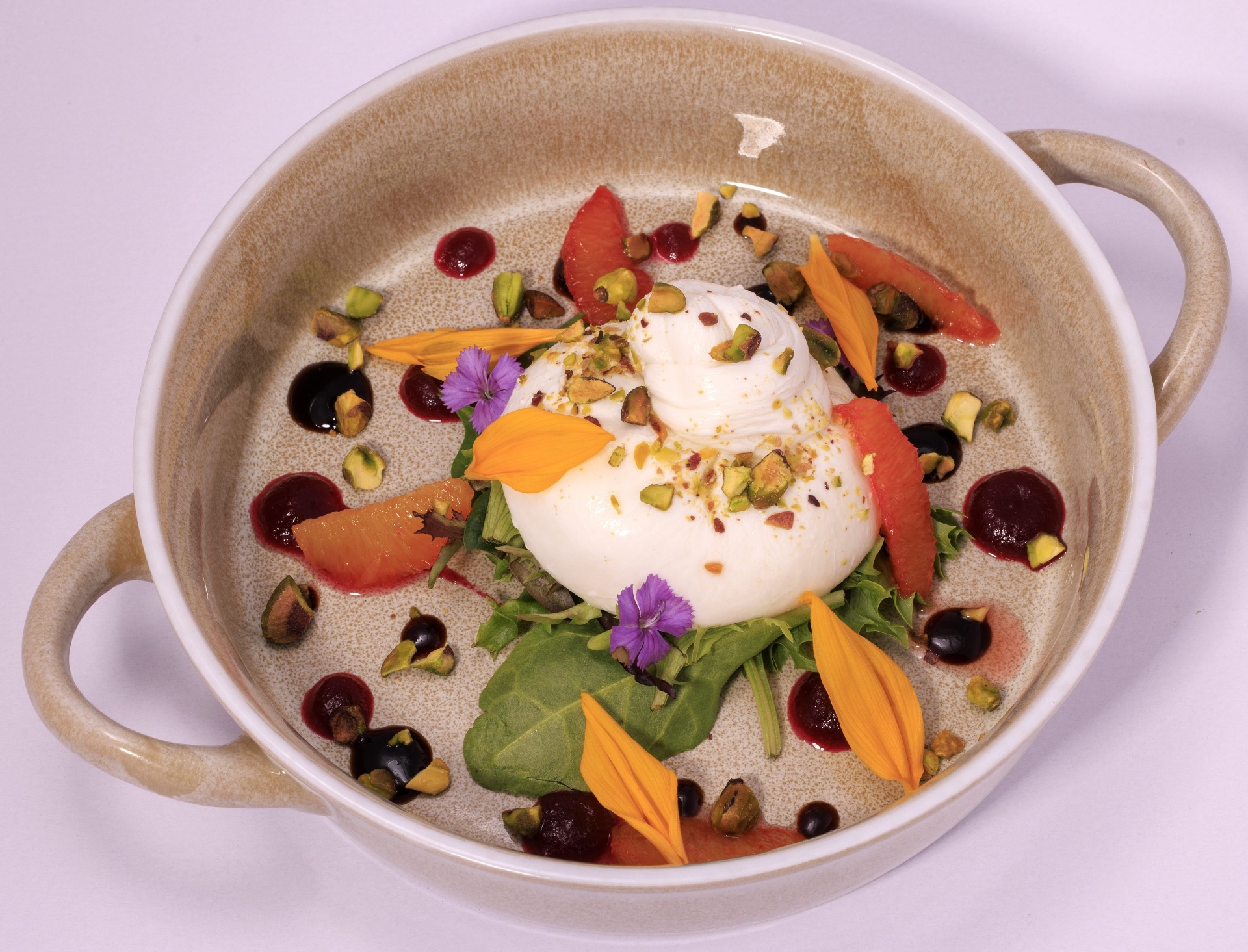 Burrata with pistachios, edible flowers and berry reduction