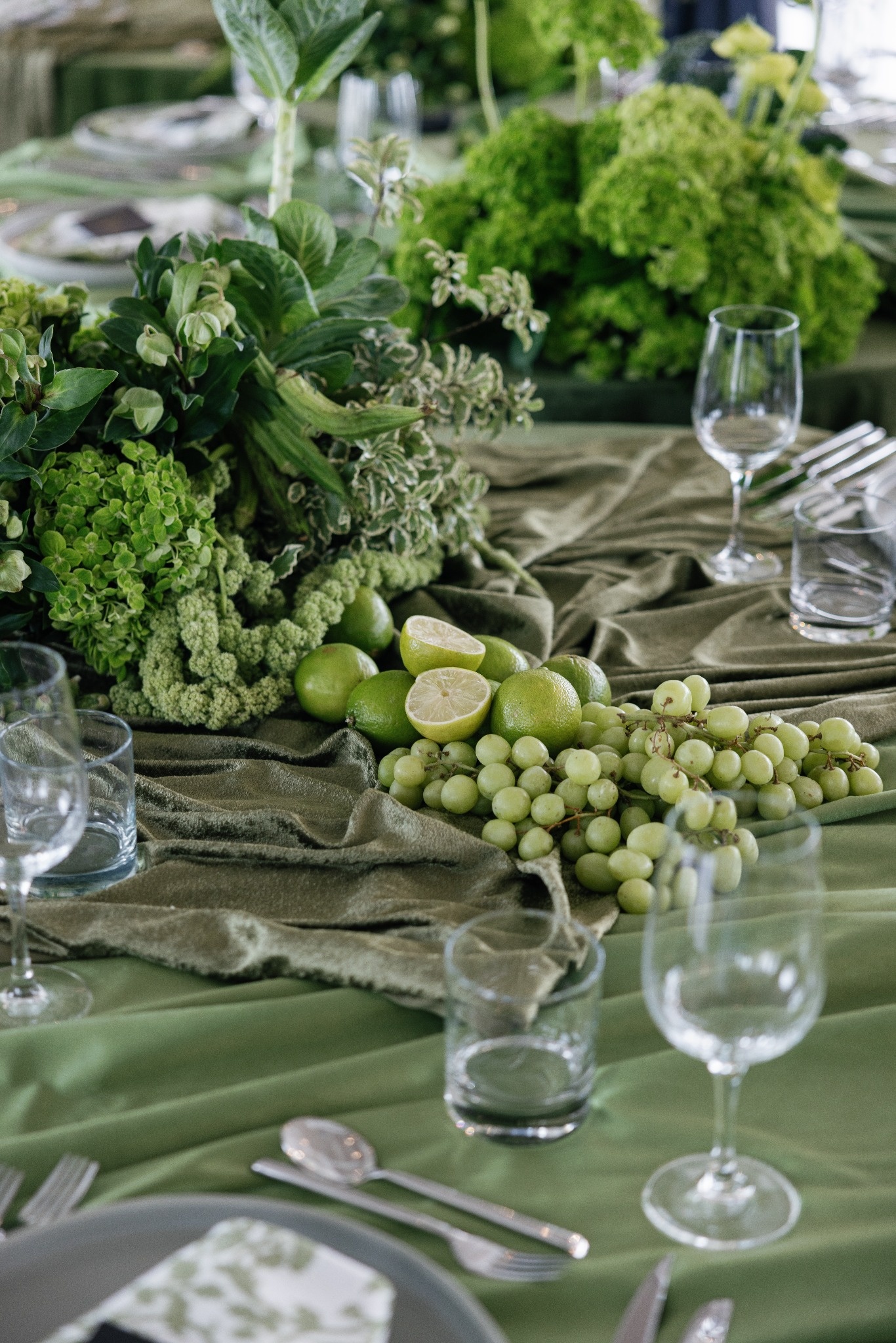 Elegant green tablescape with grapes, limes and botanical arrangements